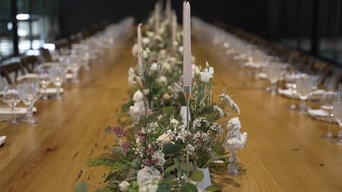 Elegant dining table setup with floral centerpieces and candles for a formal event.