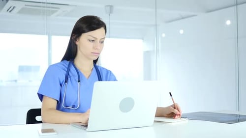 Female Doctor Working Diligently on Laptop in Office