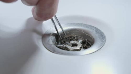 Dirty Hairs and Dirt Being Pulled from Bathtub Sink with Tweezers CU