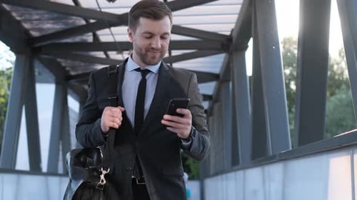 Man in Business Clothes Checking His Phone While Walking Outside in Office Buildings