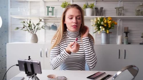 Mujer vloguera aplica lápiz labial en los labios, bloguera de belleza, mujer filmando una rutina diaria de maquillaje, tutorial