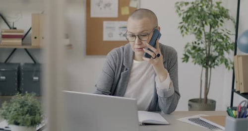 Successful Young Woman Speaking on Mobile Phone and Using Laptop Working in Office Alone