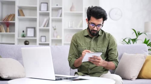 Young Adult Working on Laptop and Writing Notes