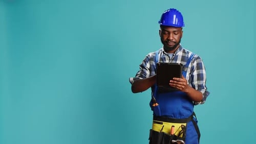 Man in Hardhat Using Tablet on Blue Background