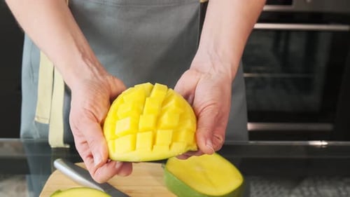 Nahaufnahme von Mango und Mangowürfeln. Das Mädchen hält eine Mango in der Hand. Gesundes Essen und Diät