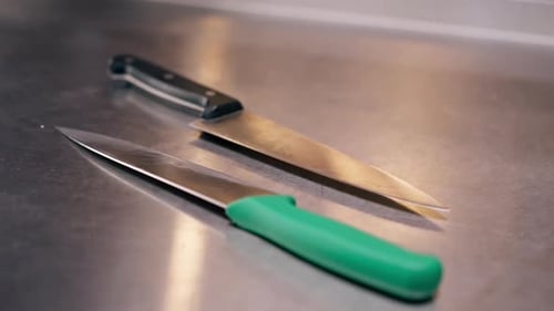 Closeup of Large Slicing Knives Lying on a Metal Table in Professional Kitchen