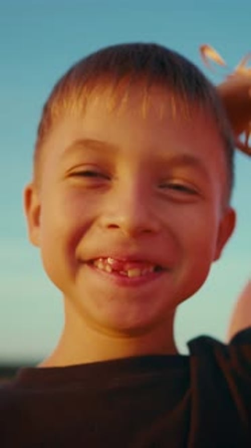 Joyeux garçon de six ans souriant à la caméra avec joie, portrait vertical d'un enfant insouciant sans personne