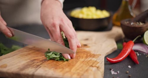 Woman Cutting and Chopping Cilantro or Parsley Greens on a Wooden Cutting Board at Domestic Kitchen