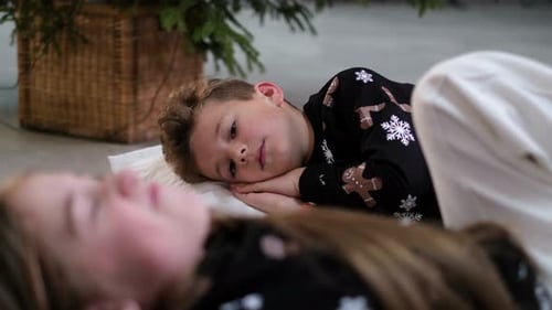 As crianças estão dormindo perto da árvore de Natal e estão esperando os presentes de Natal do Papai Noel