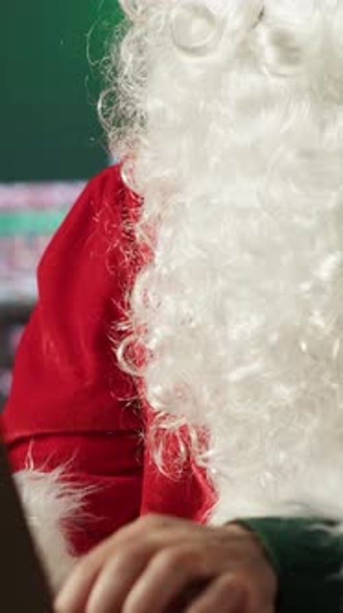 Vertical Video Santa Claus Uses a Laptop in His Festive Log Cabin Navigating Online Webpages