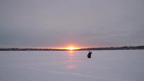 Man Standing on Frozen Lake at Sunset