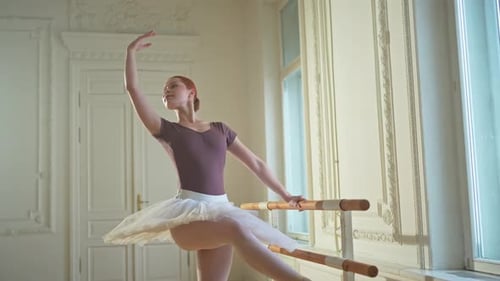 Ballet Dancer Practicing at the Barre Indoors
