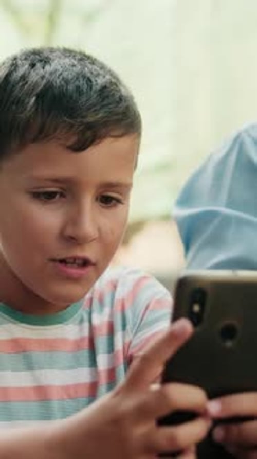 Vertical video, Grandfather And Grandson Use Smartphone In Park