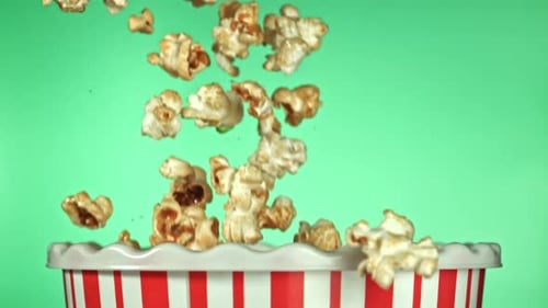 Falling Popcorn Filling Striped Container against Green Background