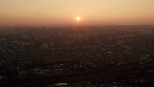 The Drone Flies Into the City at Sunset in Smoke and Smog Polluted City