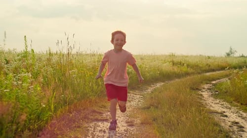 Slow Motion Lifestyle Video of a Boy Running Across a Field in the Sun
