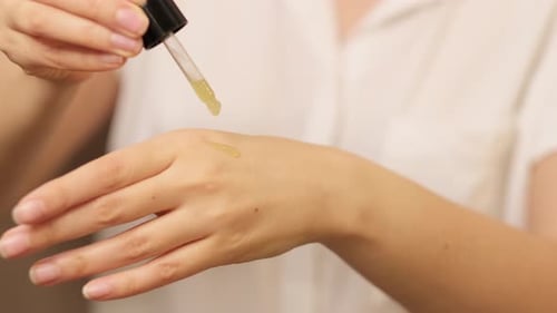 Woman Applies Cosmetic Oil to Hand