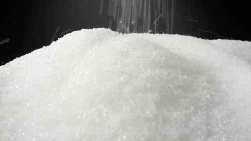 White sugar delicately cascading onto a sleek black background