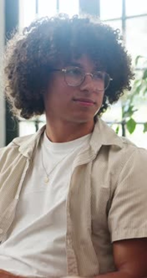 Young Man with Curly Hair Explaining Something Indoors