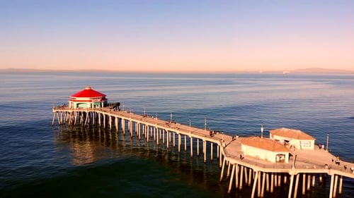 Huntington Beach Pier aerial 4k drone flyover with dIner and bait shops visible, Pacific Ocean at su