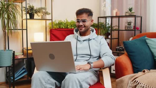 Young Adult Chatting On Laptop Computer Indoors