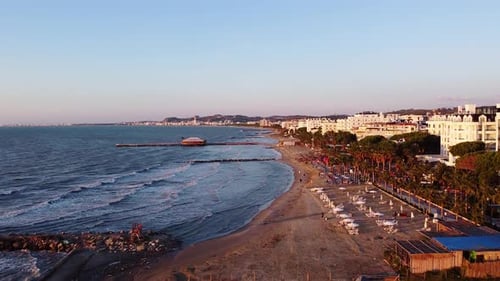 Aerial above sandy beach during golden hour in suburb of Durres, Albania.