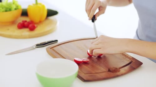 Woman Cutting Fresh Cherry Tomatoes on Cutting Board