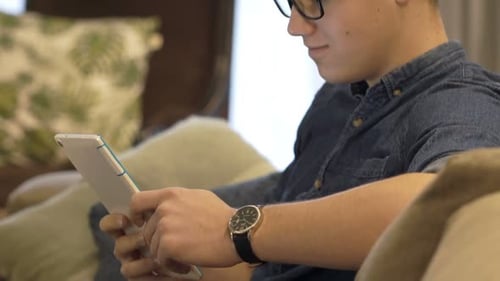 Young Man Using Tablet on Couch Indoors