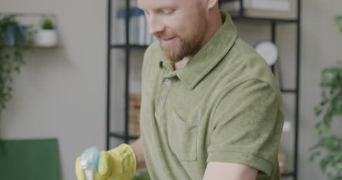 Man Cleans Desk with Spray and Cloth