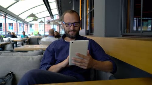 Young Handsome Man with Tablet Computer Sitting in Cafe 30s