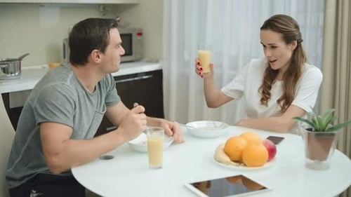 Couple Eating Breakfast and Toasting Juice Indoors