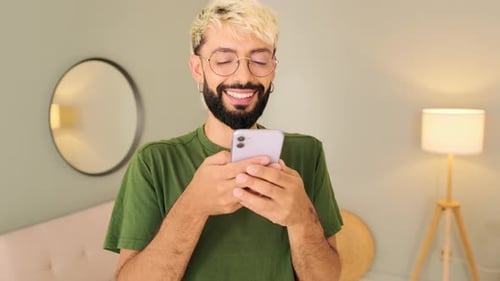 Smiling Man Looking at Smartphone Indoors