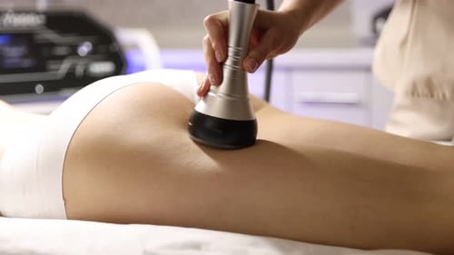 Woman undergoing cellulite treatment with radio frequency machine in salon, closeup