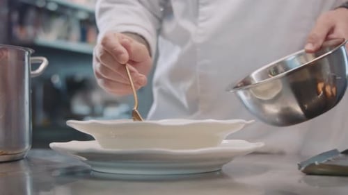 Cook Holding Spoon in Hand Finishing Dish By Chef in Restaurant Kitchen Ready for Service to