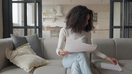 Woman Reviews Documents on Couch in Bright Home