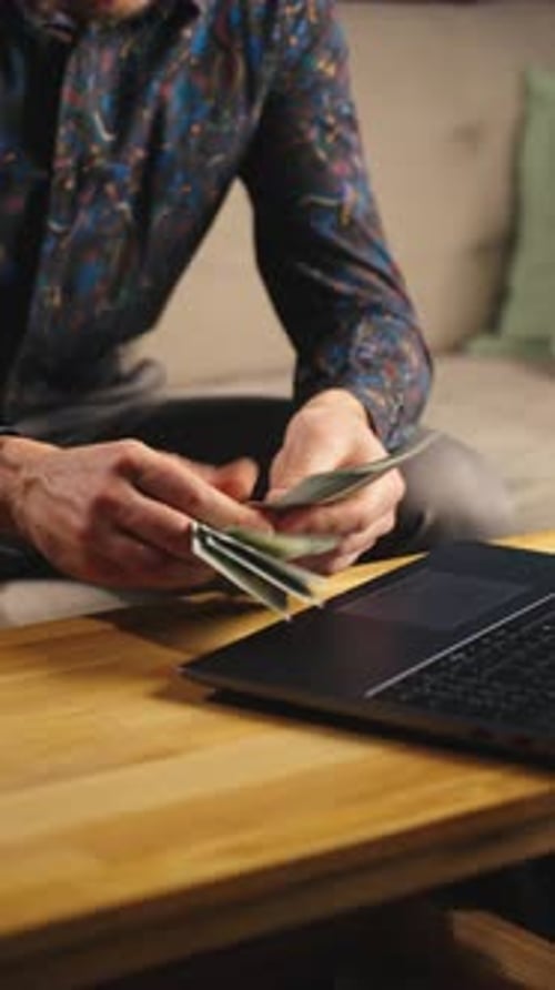 Person Counting Cash at Desk with Laptop