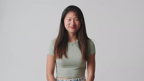 Young woman looking at camera smiling and laughing isolated over white background in studio