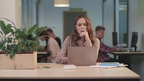 Woman Meditating at Desk with Coworkers in Background