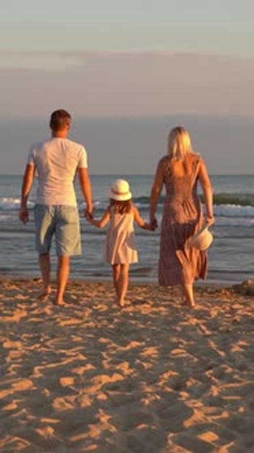 Family Walk on Sea Beach at Sunset Father Mother and Daughter Summer Vacation