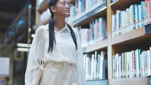 Uma mulher andando perto das estantes de livros em uma biblioteca