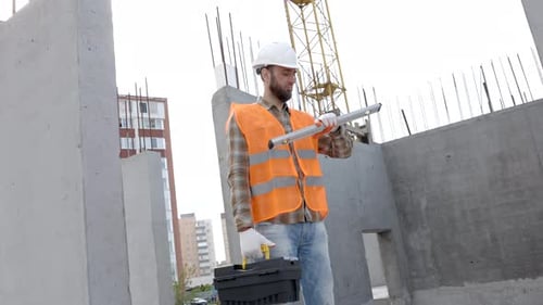 Builder repairman, foreman in protective helmet stands at workplace in building and holds ruler