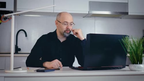 Man in Kitchen Talking on Computer