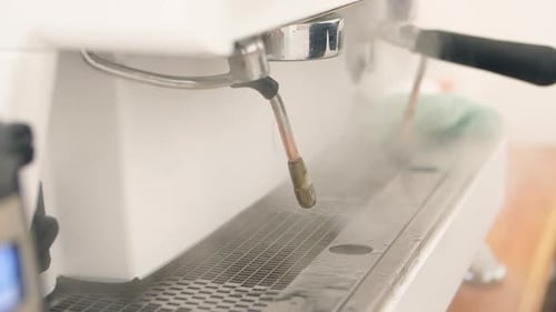Commercial espresso coffee blowing steam from steam wand in coffee shop