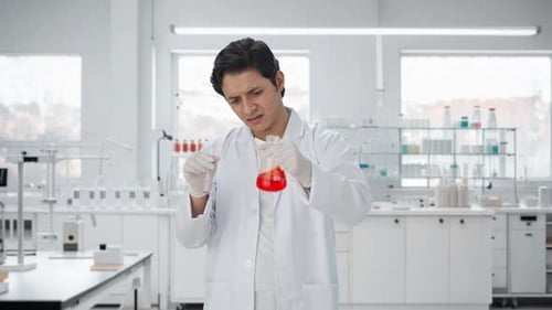 Concentrated Scientist Mixing Red Liquid in Laboratory