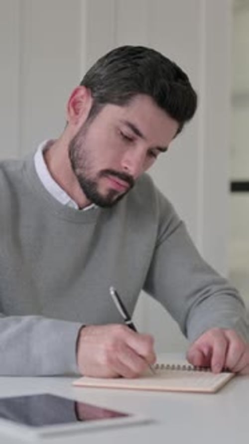 Young Man Writing on Paper in Office, Vertical Video