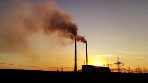 Evening background of industrial factory. Dirty smoke goes from pipes at sunset.