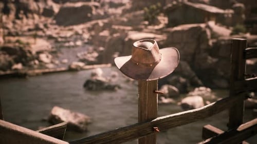 A Weathered Cowboy Hat Resting on a Wooden Post Near a Tranquil River
