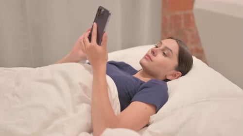 Latina Woman using Smartphone while Lying in Bed