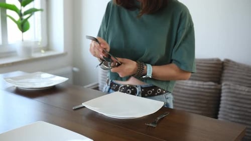 Woman Setting Wooden Dining Table With Plates, Silverware