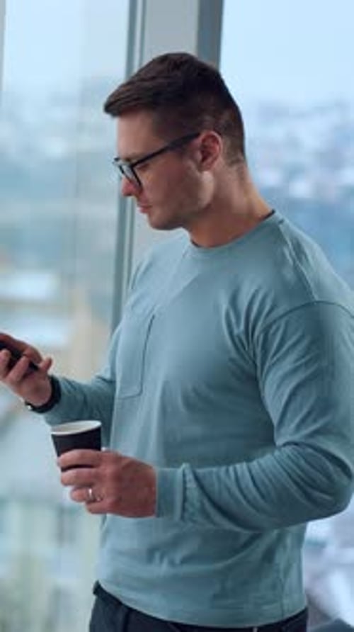 Man Uses Phone with Coffee in Modern Office